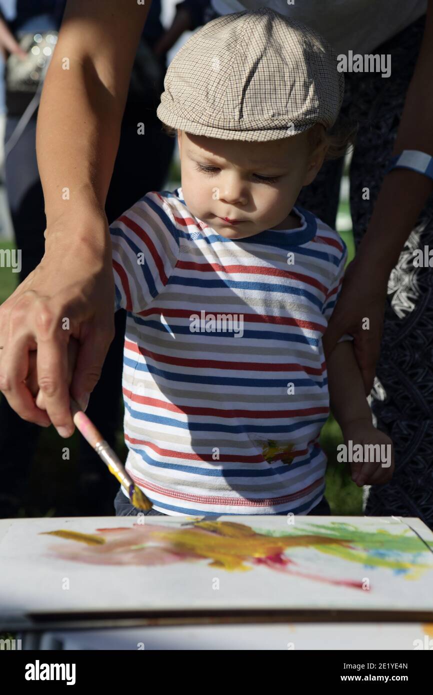 Parent helping his son to paint in park Stock Photo