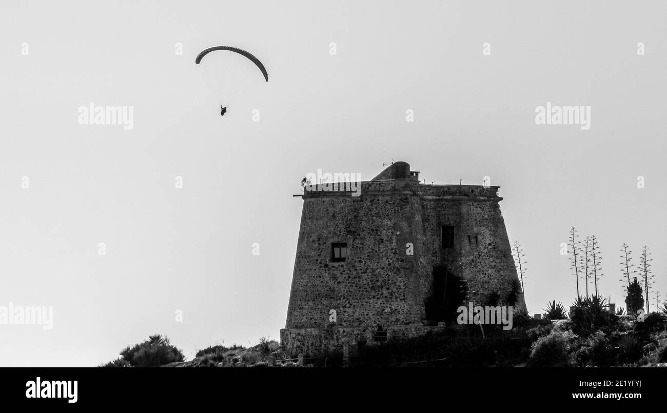 Silhouette of a paraglider flying over the medieval Tower of Tamaray in Almuñécar (Spain) Stock Photo