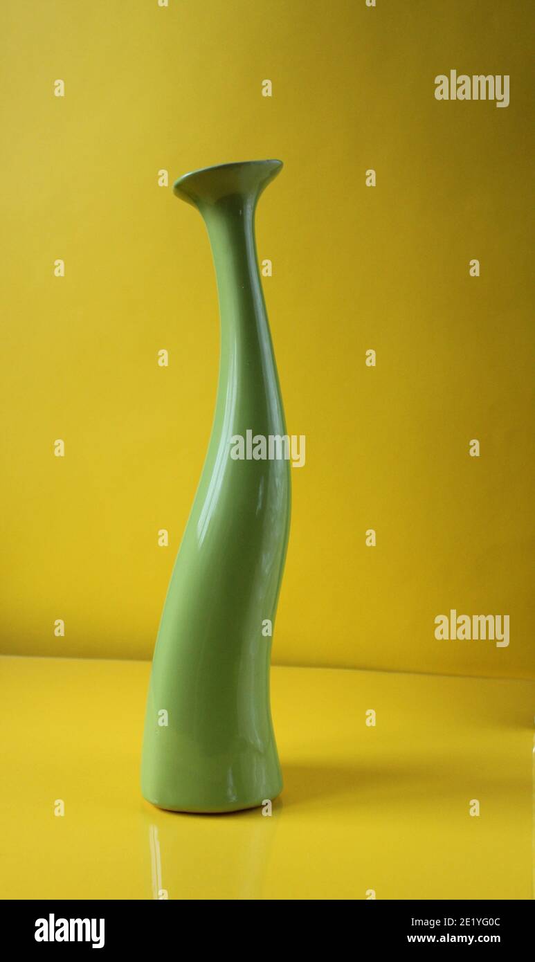 Green asymetric vase on trend color Illuminatiited yellow background with copyspace place for text. Stock Photo