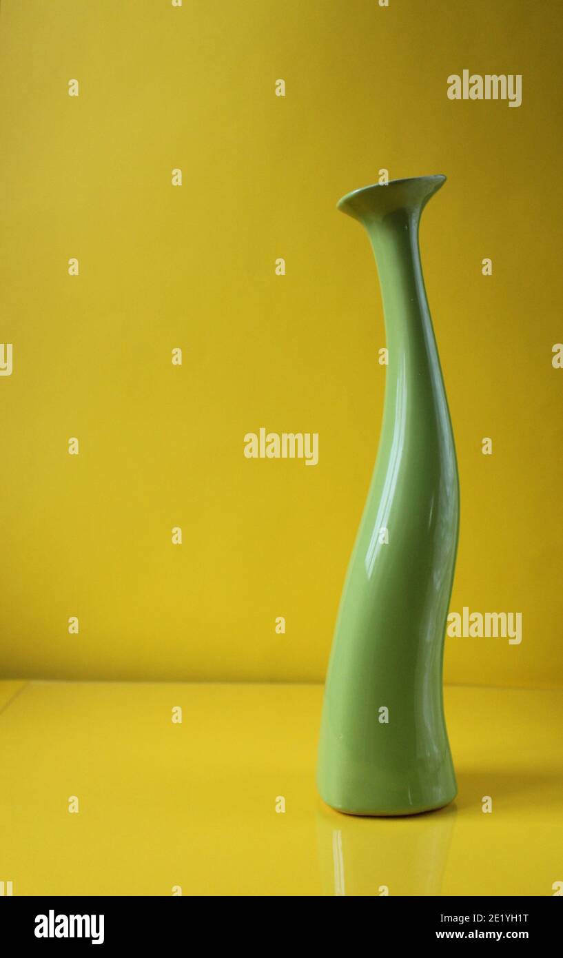 Green asymetric vase on trend color Illuminatiited yellow background with copyspace place for text. Stock Photo