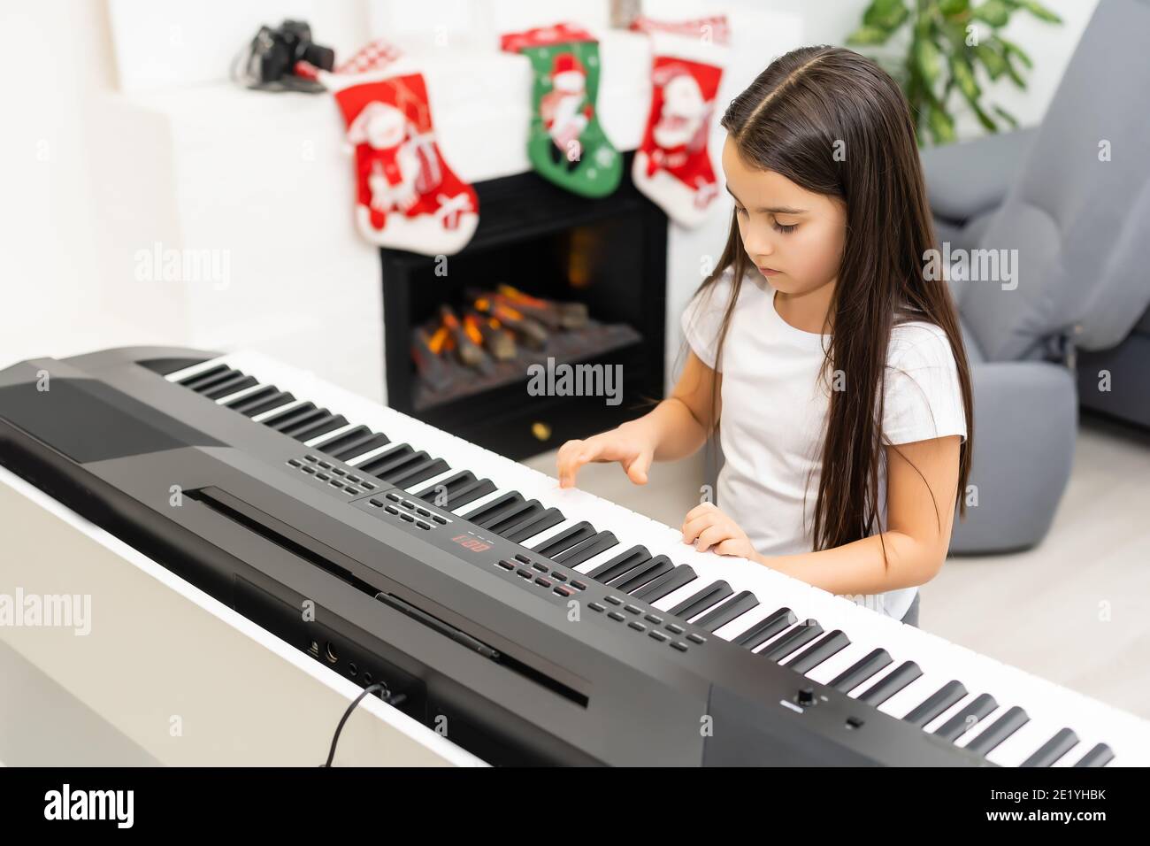 Cute little girl play Christmas melody on piano, merry Christmas celebration, happy seasonal holidays Stock Photo