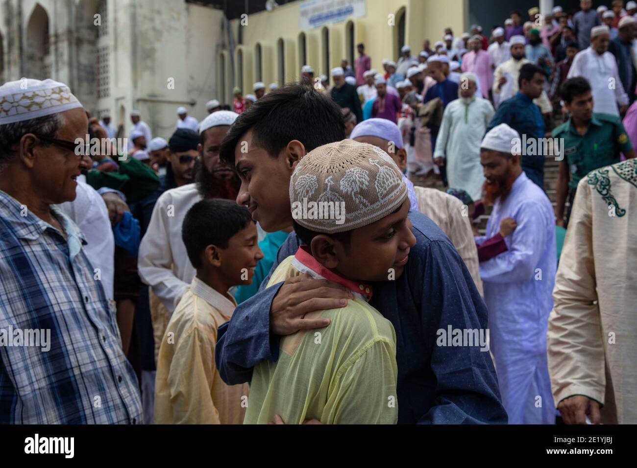 Boys embrace each other after Eid prayers at the Baitul Mokarram
