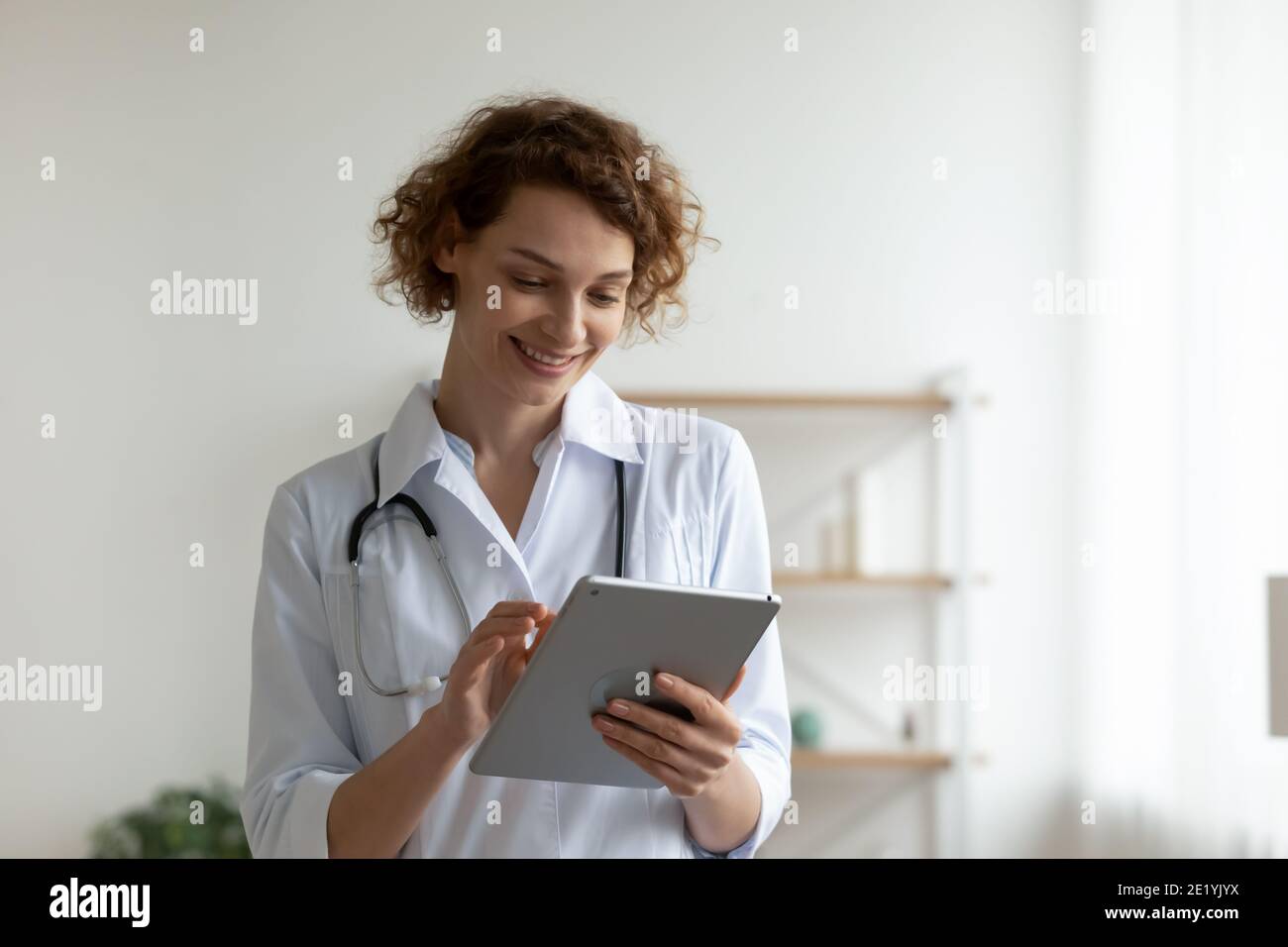 Happy young professional general practitioner using digital computer tablet. Stock Photo