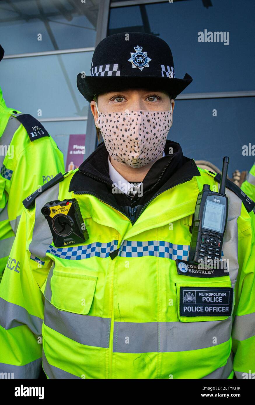 Young female London Police constable wearing a face mask on Clapham High Street during the anti-lockdown demonstration on January 9, 2021 in London. Stock Photo
