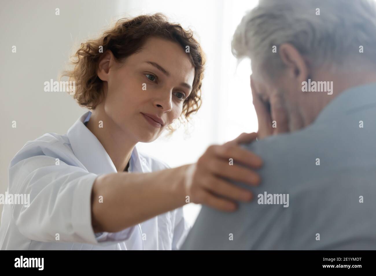 Compassionate young general practitioner doctor supporting desperate man. Stock Photo