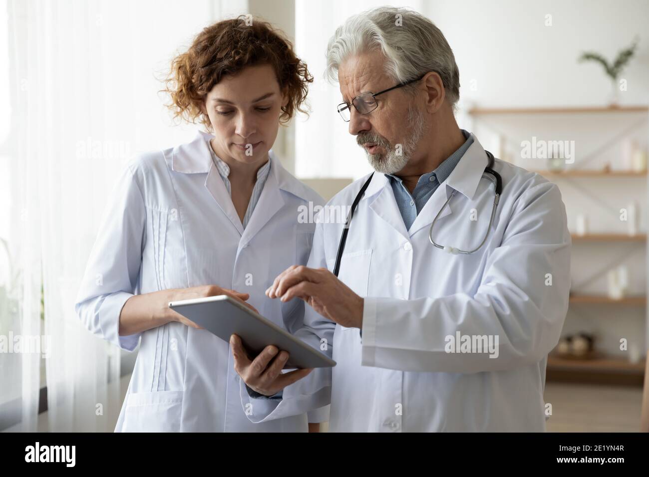 Focused two different generations doctors using computer tablet Stock