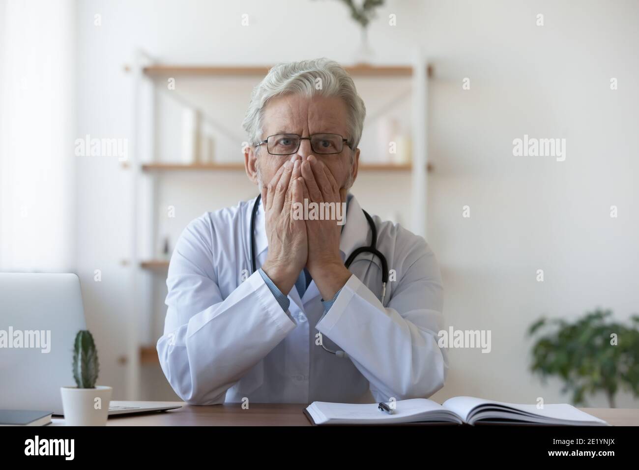 Confused old mature doctor therapist regretting diagnosis mistake. Stock Photo