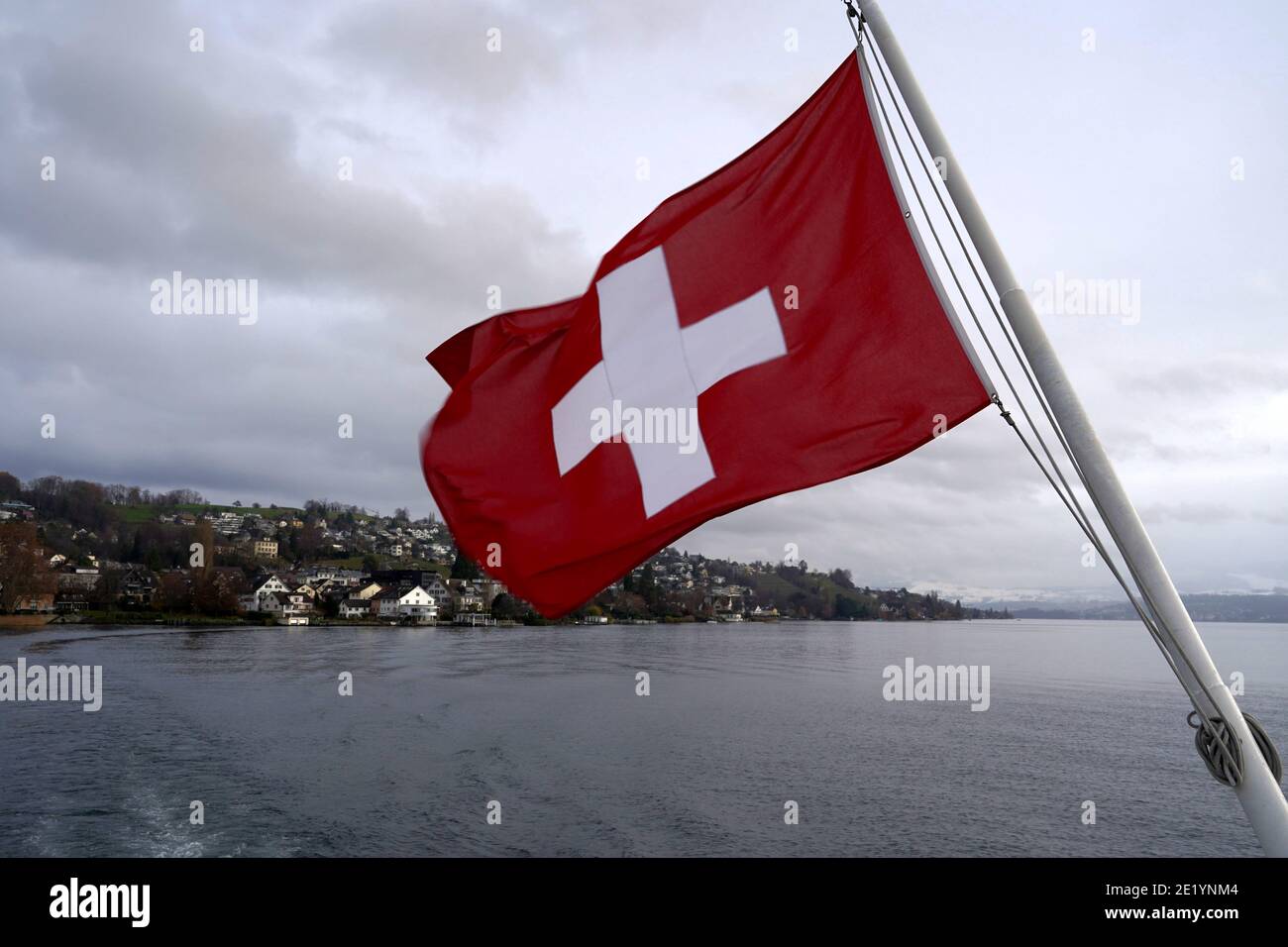 Swiss federal flag blowing in the wind over Lake Zurich. Stock Photo