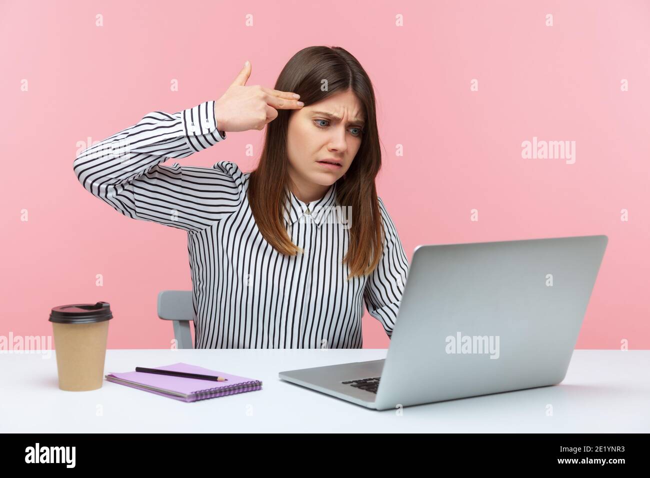 Depressed woman office worker holding finger gun near head talking