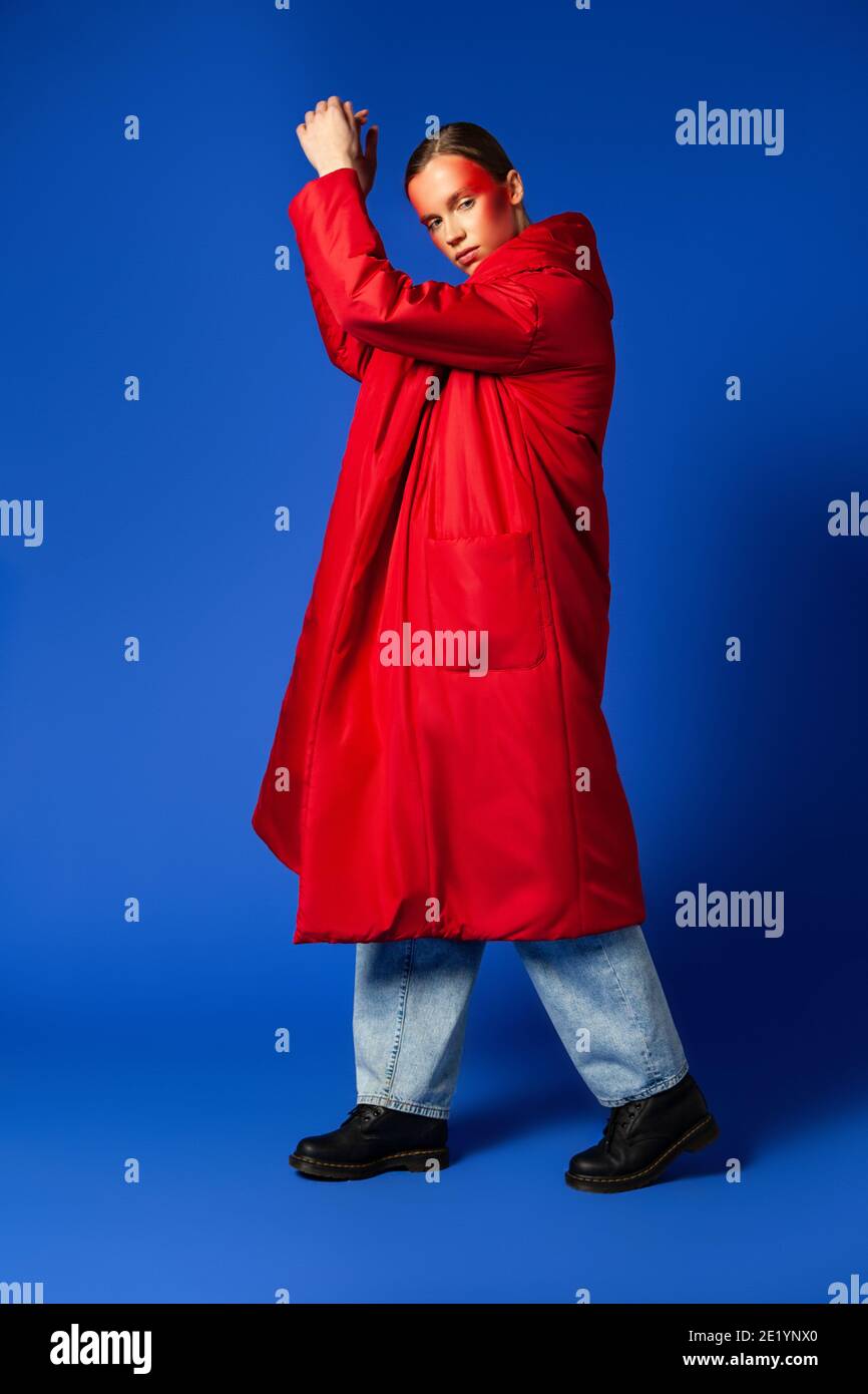 Trendy female dancing on tiptoes against blue background Stock Photo