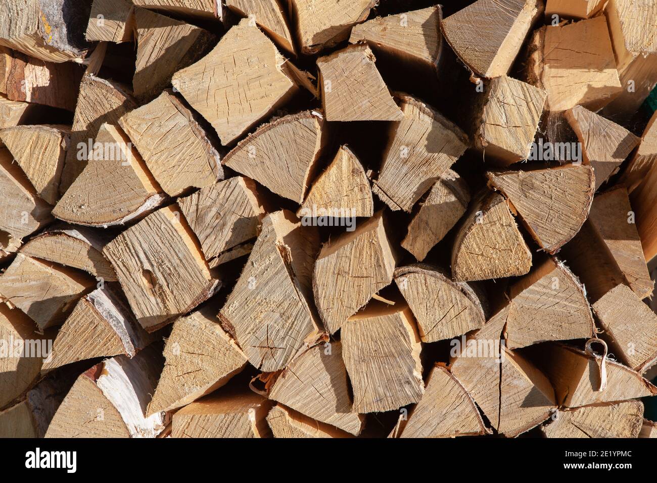 Background from stack of firewood from birch tree, for heating house, stacked in backyard, uncut