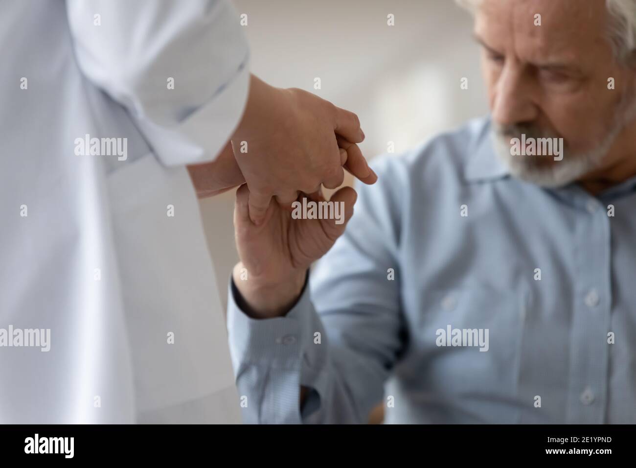 Young compassionate female physician supporting older patient. Stock Photo