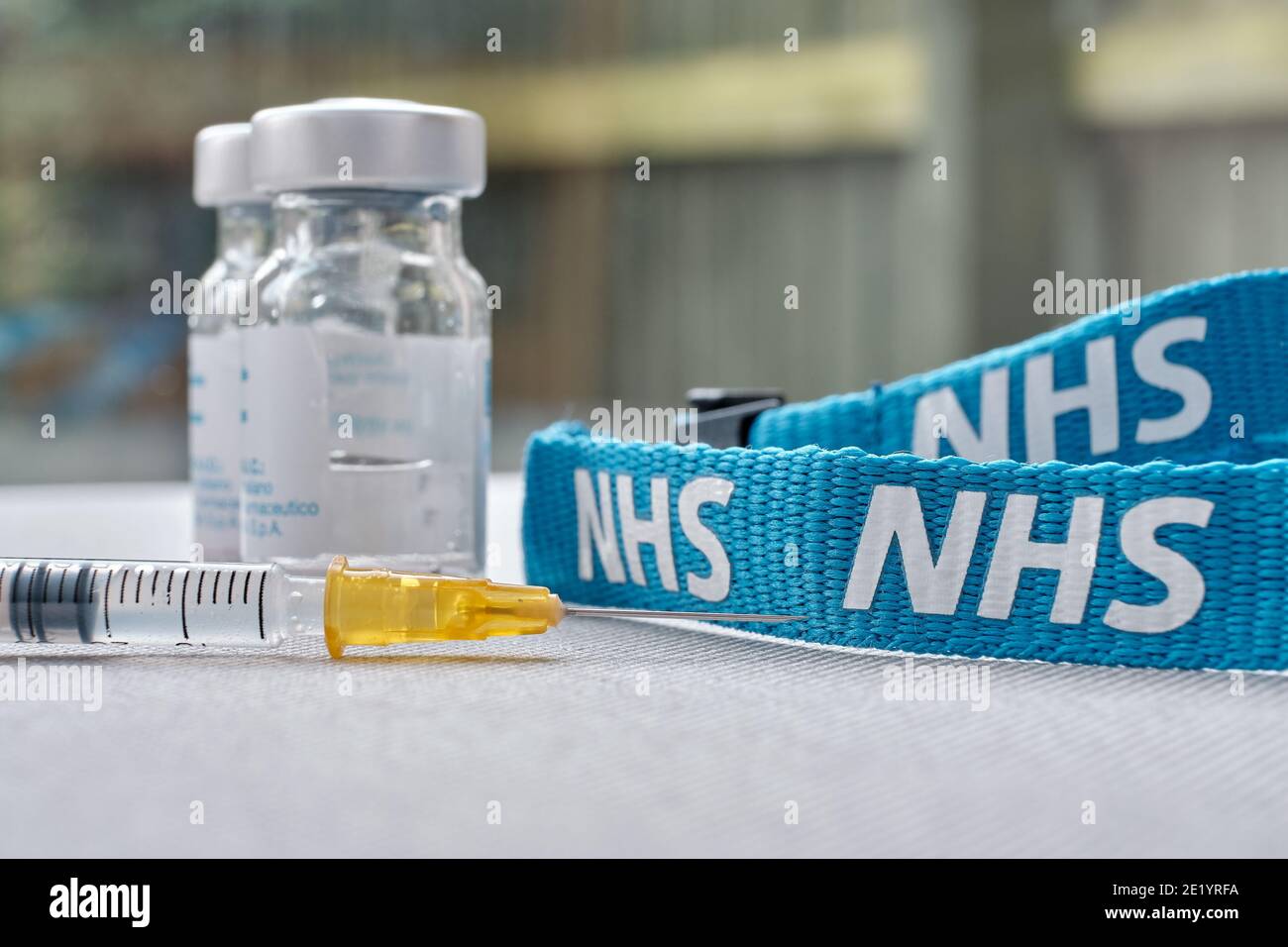 Stafford, United Kingdom - January 10 2021: NHS vaccine concept. Syringe, injection vials and NHS lanyard. Selective focus. Stock Photo