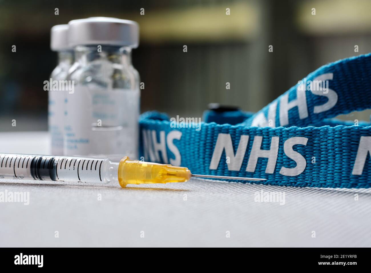 Stafford, United Kingdom - January 10 2021: NHS vaccine concept. Syringe, injection vials and NHS lanyard. Selective focus. Stock Photo