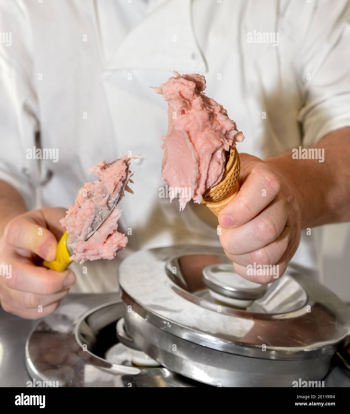 Hands of the ice cream man scooping strawberry ice cream into the waffle cone Stock Photo