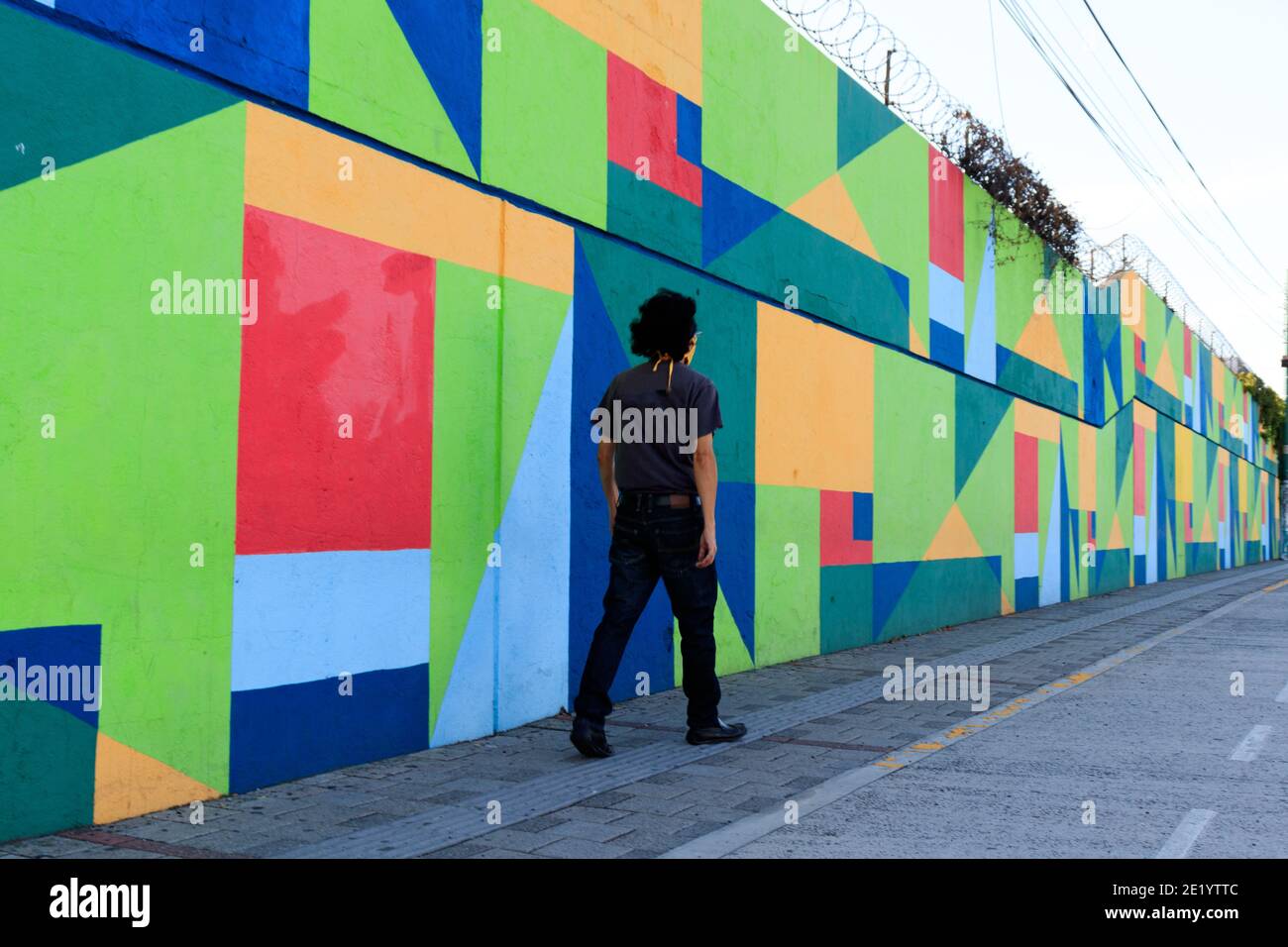 man with a yellow face mask in front of a colorful wall Stock Photo