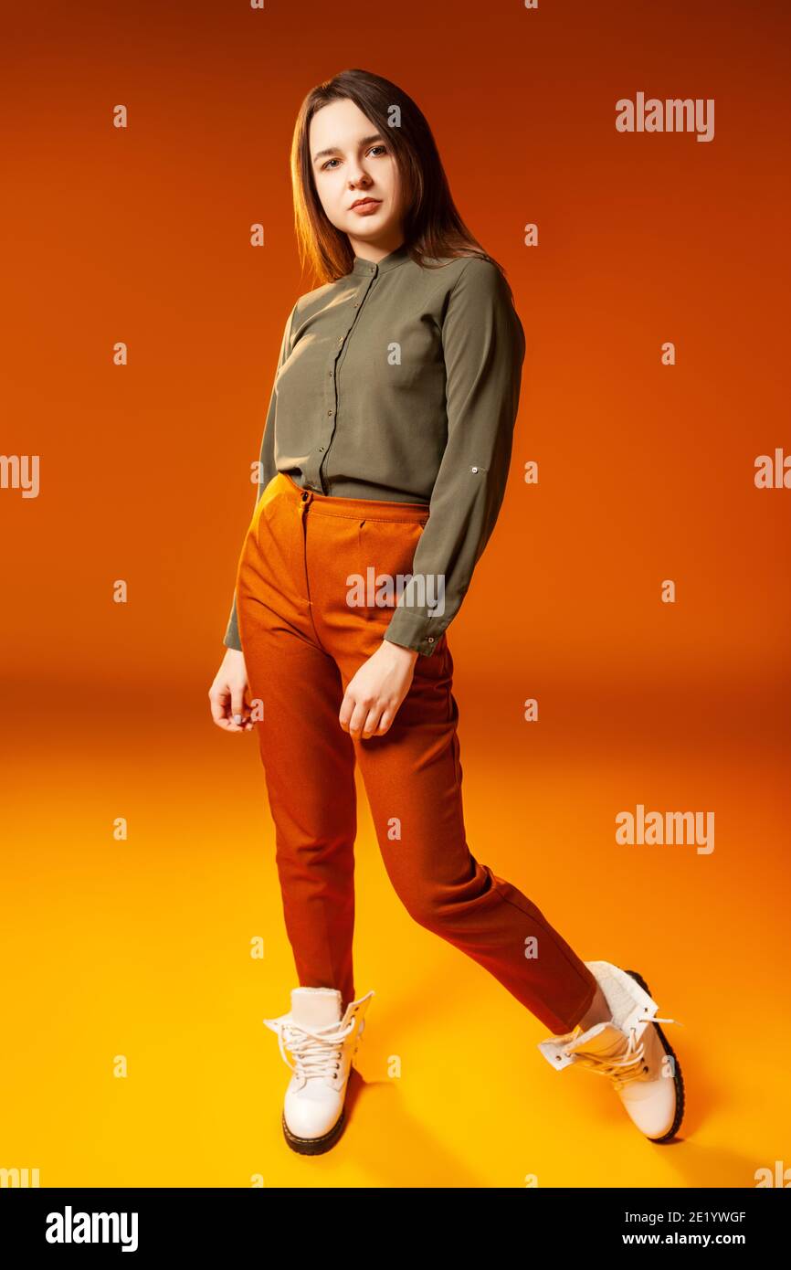 Trendy young woman looking at camera against orange background Stock Photo