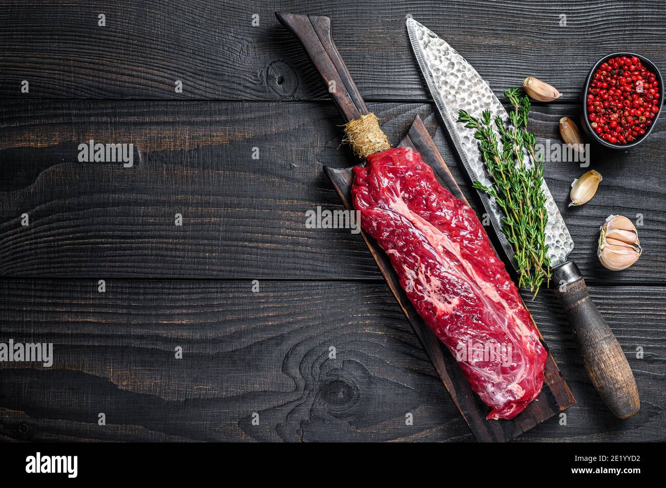 Raw Onglet Hanging Tender beef meat steak on a wooden cutting board. Black wooden background. Top view. Copy space Stock Photo