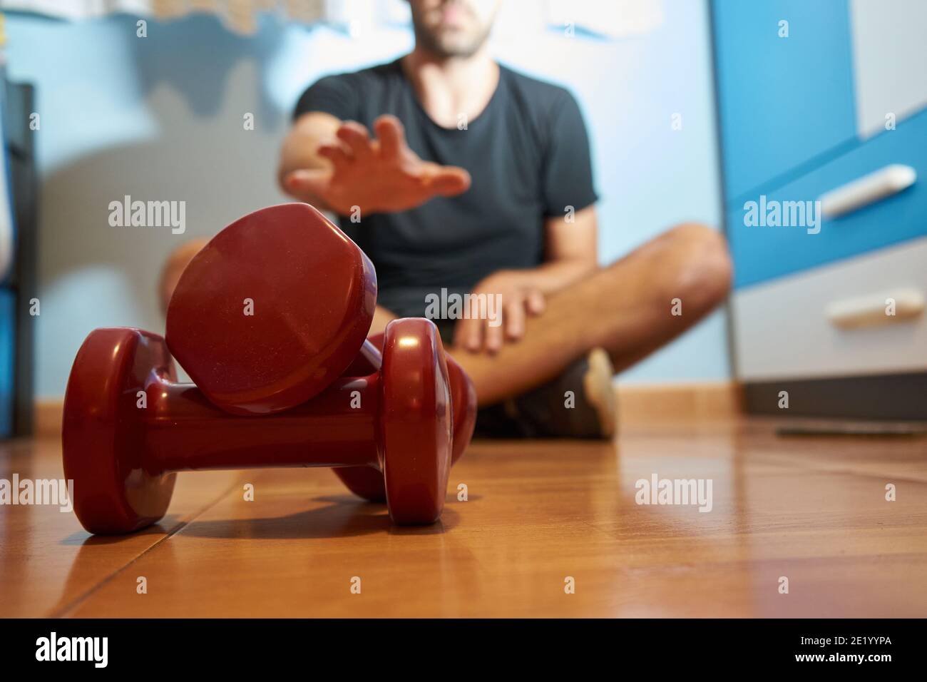 Man in his bedroom is going to do sport with weights, selective approach Stock Photo