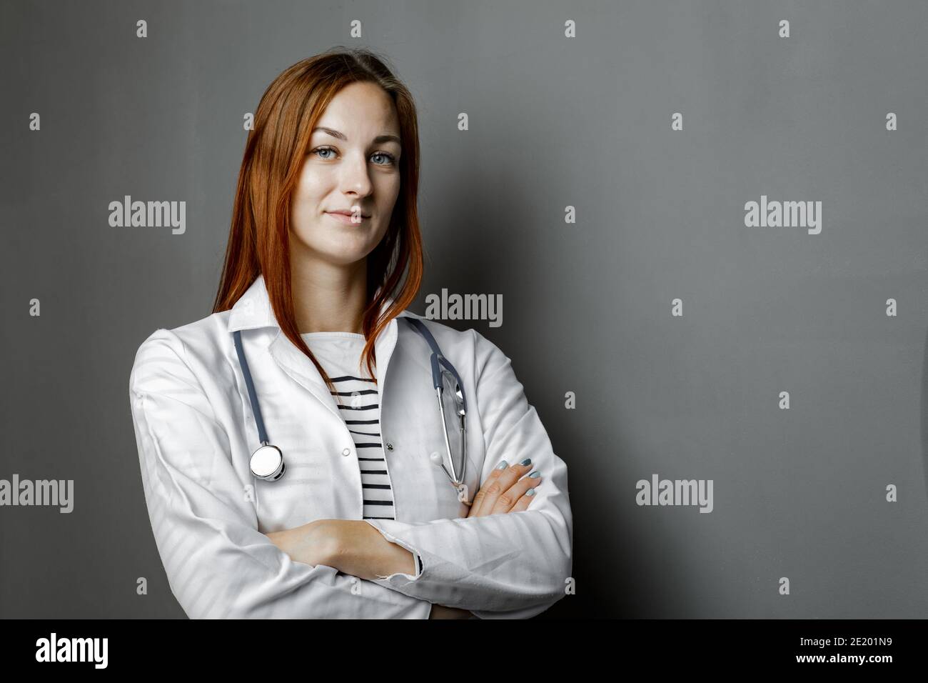 Portrait of glad smiling doctor in white uniform standing with crossed ...