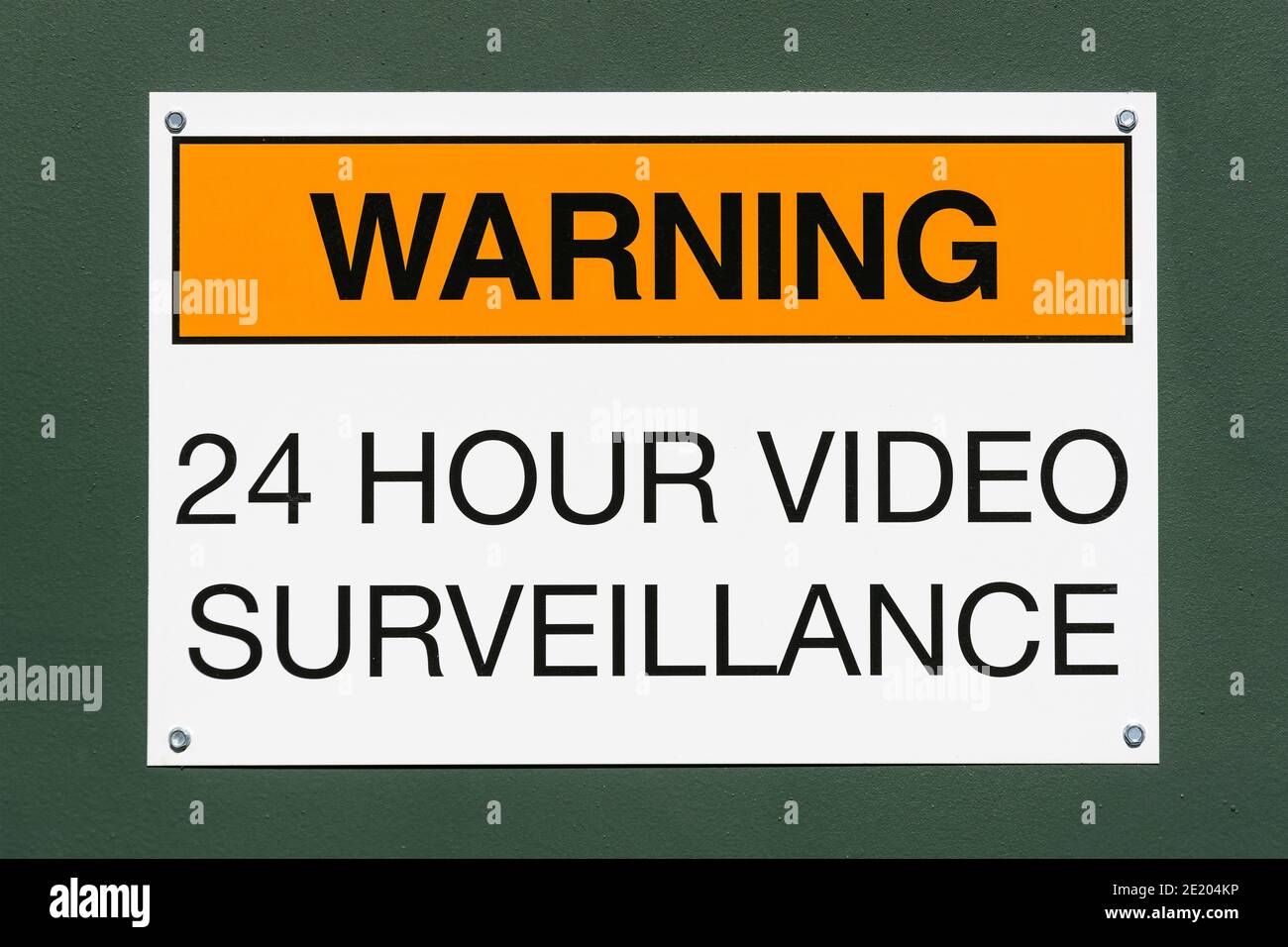 Warning 24 hour video surveillance sign on green metal background. Stock Photo