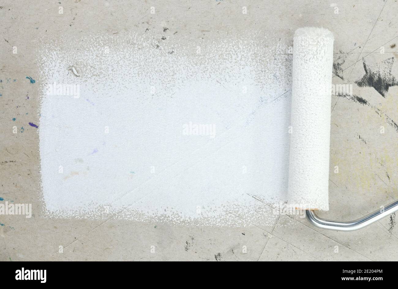 Painting a rough wall with roller. Paint roller leaving stroke of white