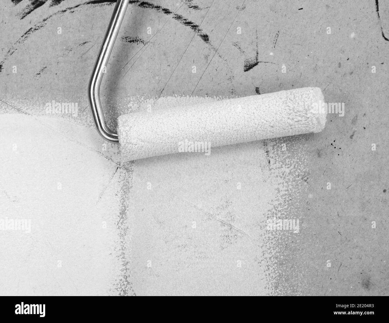 Painting a rough wall with roller. Paint roller leaving stroke of white