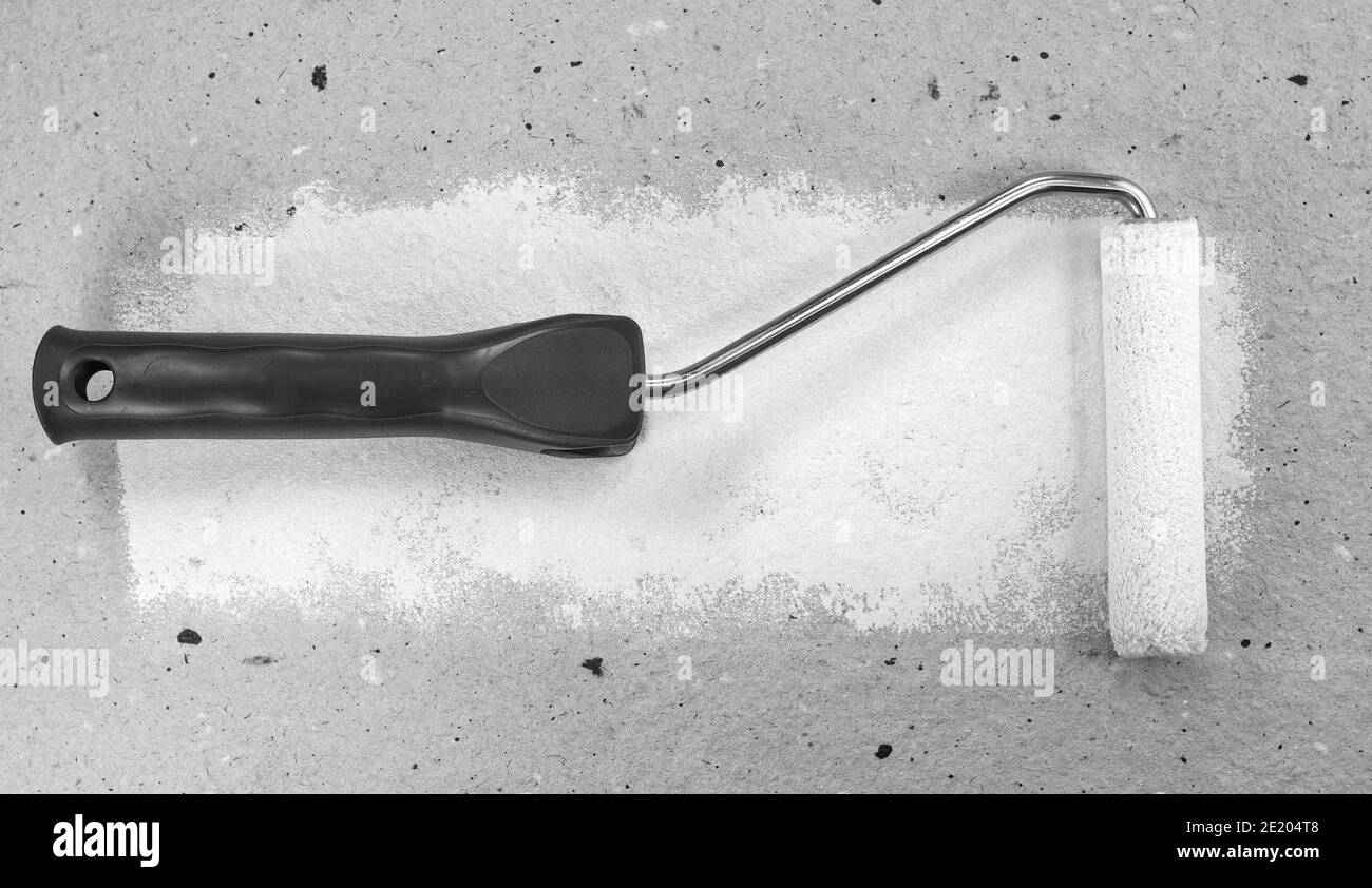 Painting a rough wall with roller. Paint roller leaving stroke of white