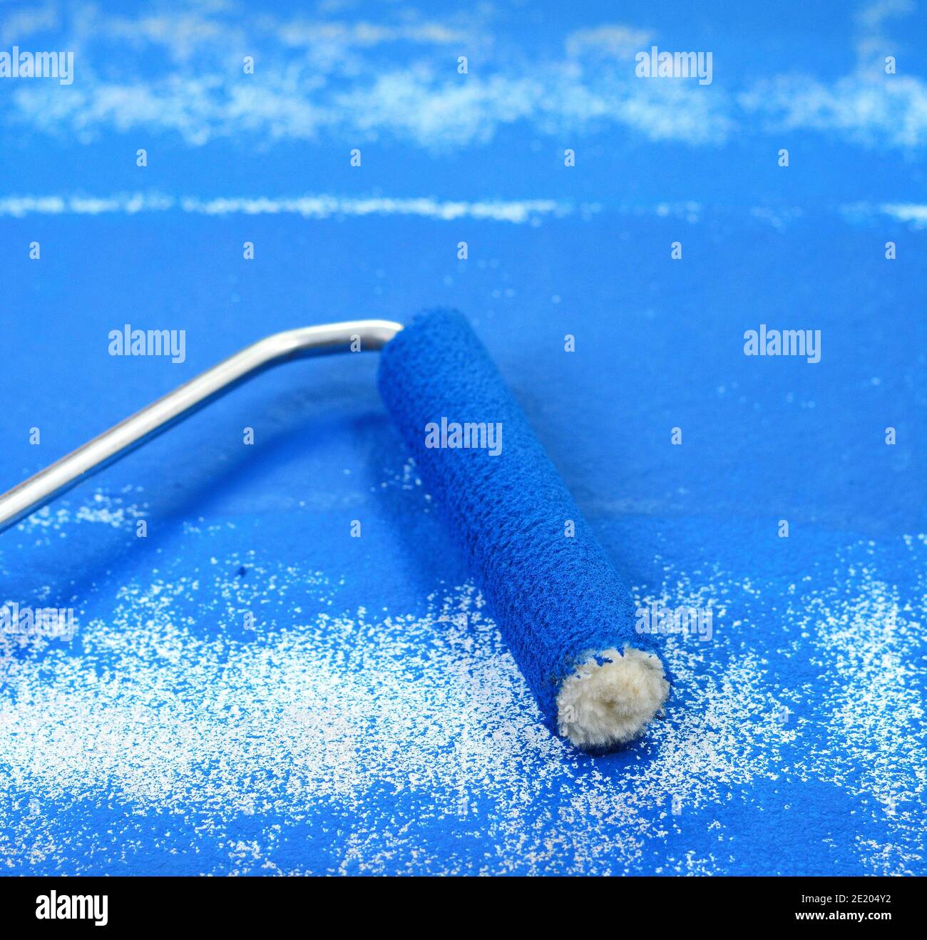 Painting a rough wall with roller. Paint roller leaving stroke of white