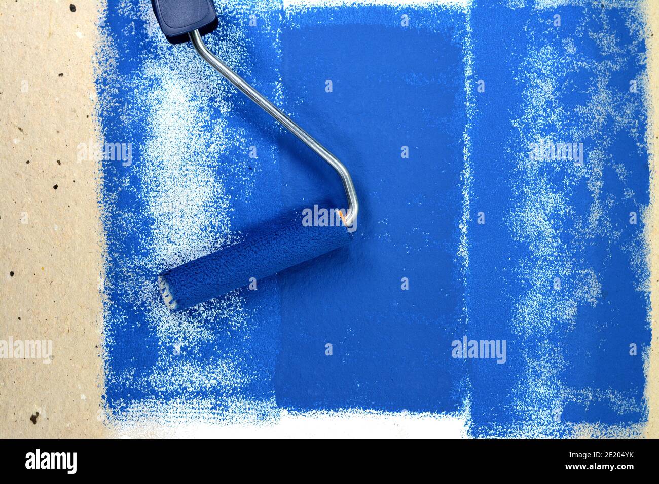 Painting a rough wall with roller. Paint roller leaving stroke of white