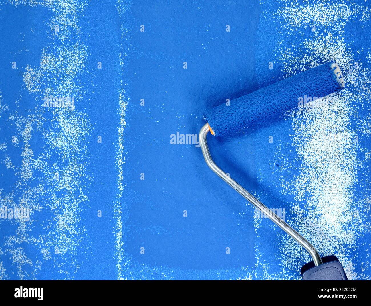 Painting a rough wall with roller. Paint roller leaving stroke of white