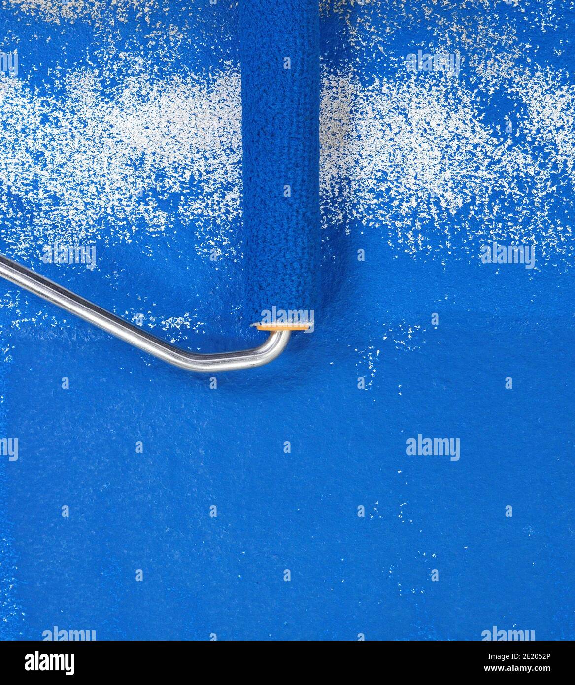 Painting a rough wall with roller. Paint roller leaving stroke of white