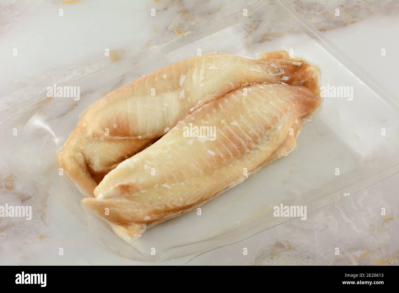 Two frozen raw tilapia fish fillets in vacuum packed airtight plastic