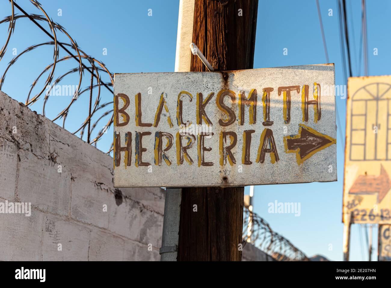 A handmade sign with an arrow points to the location of the local blacksmith. Stock Photo