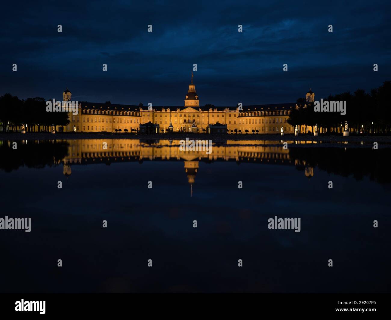 Panorama night reflection of illuminated yellow stone Schloss Karlsruhe Castle Palace Schlosspark in Baden Wurttemberg Germany in Europe Stock Photo