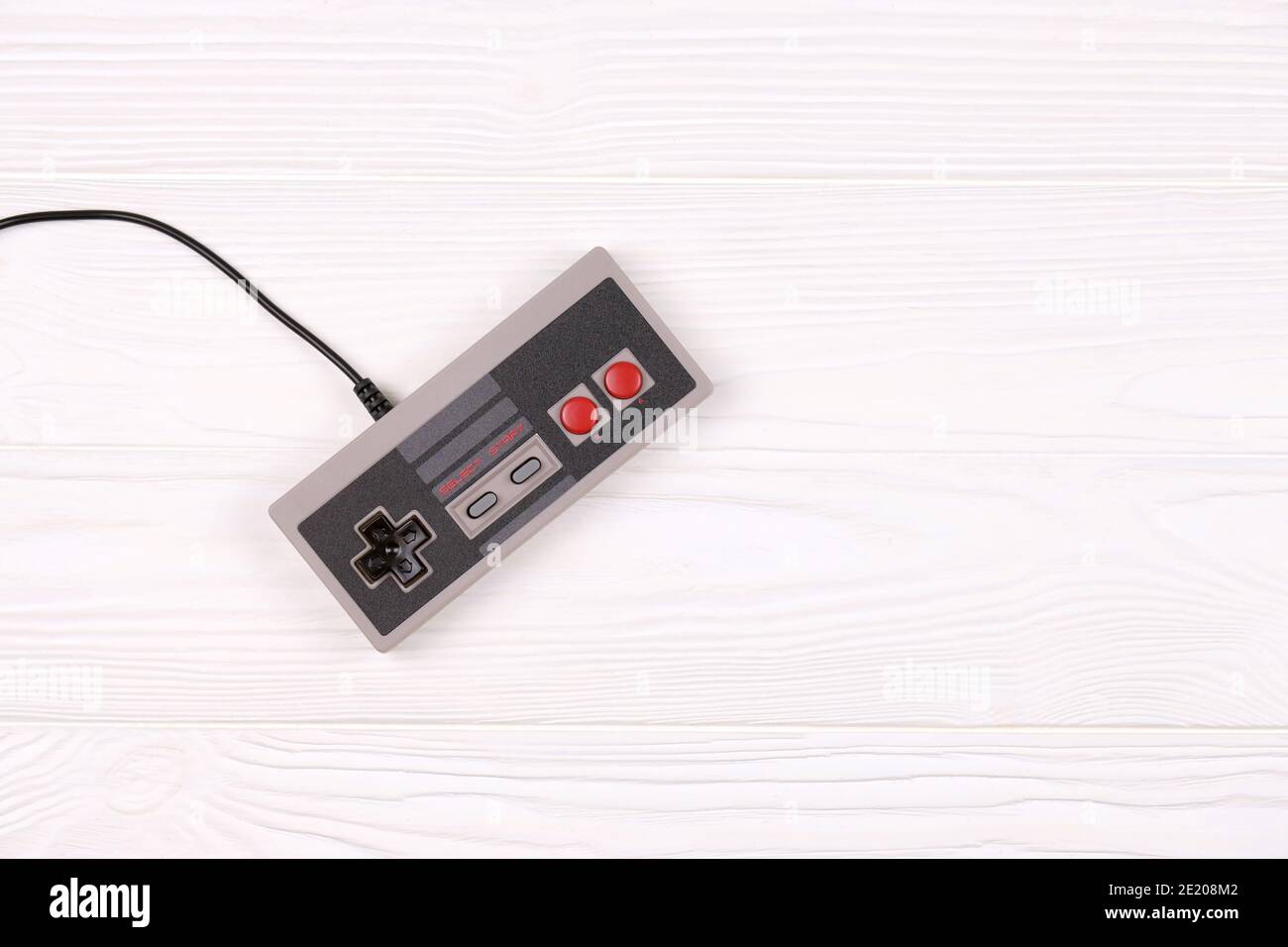 KHARKOV, UKRAINE - DECEMBER 27, 2020: Old gamepad for 8-bit video game console nintendo entertainment system and nes mini on white wooden table. Old s Stock Photo