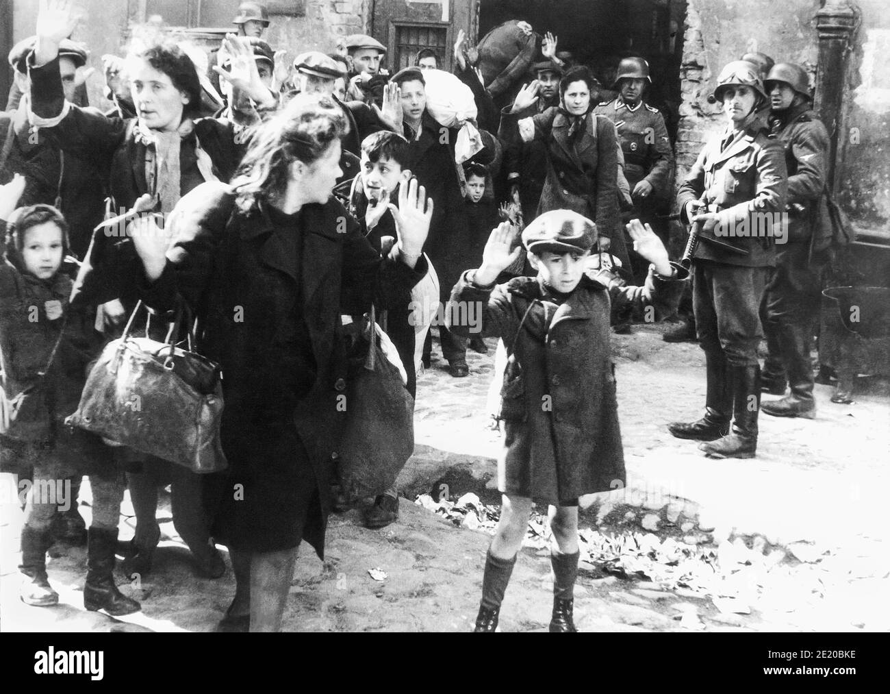 A boy raises his hands over his head as Nazi soldiers forcibly remove Polish Jews in the Warsaw Ghetto Uprising to be transported by train to Majdanek extermination camp or Treblinka. One of the most iconic photographs of WWII, the image, most likely from April or May 1943, was included in the Stoop Report given to Heinrich Himmler by SS and Police Leader Jürgen Stroop. Stock Photo