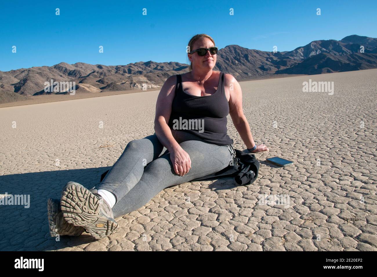 A woman poses for photos while visiting The Racetrack in Death Valley National Park. Stock Photo