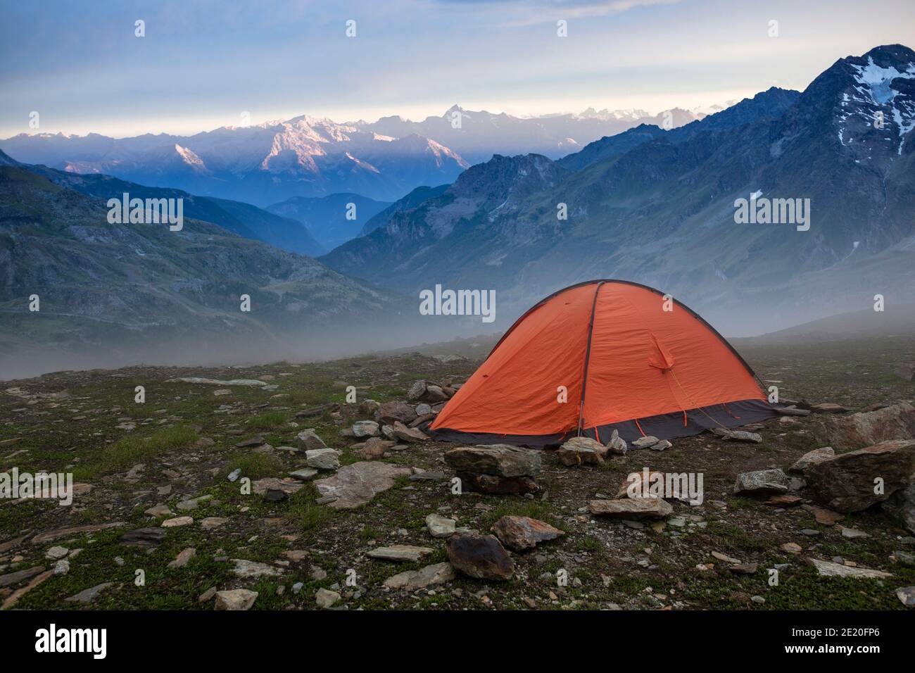 Base camp set in Alpine background. Ten set on hill i Alps mountains. Tourist shelter camp in high mountains. Stock Photo