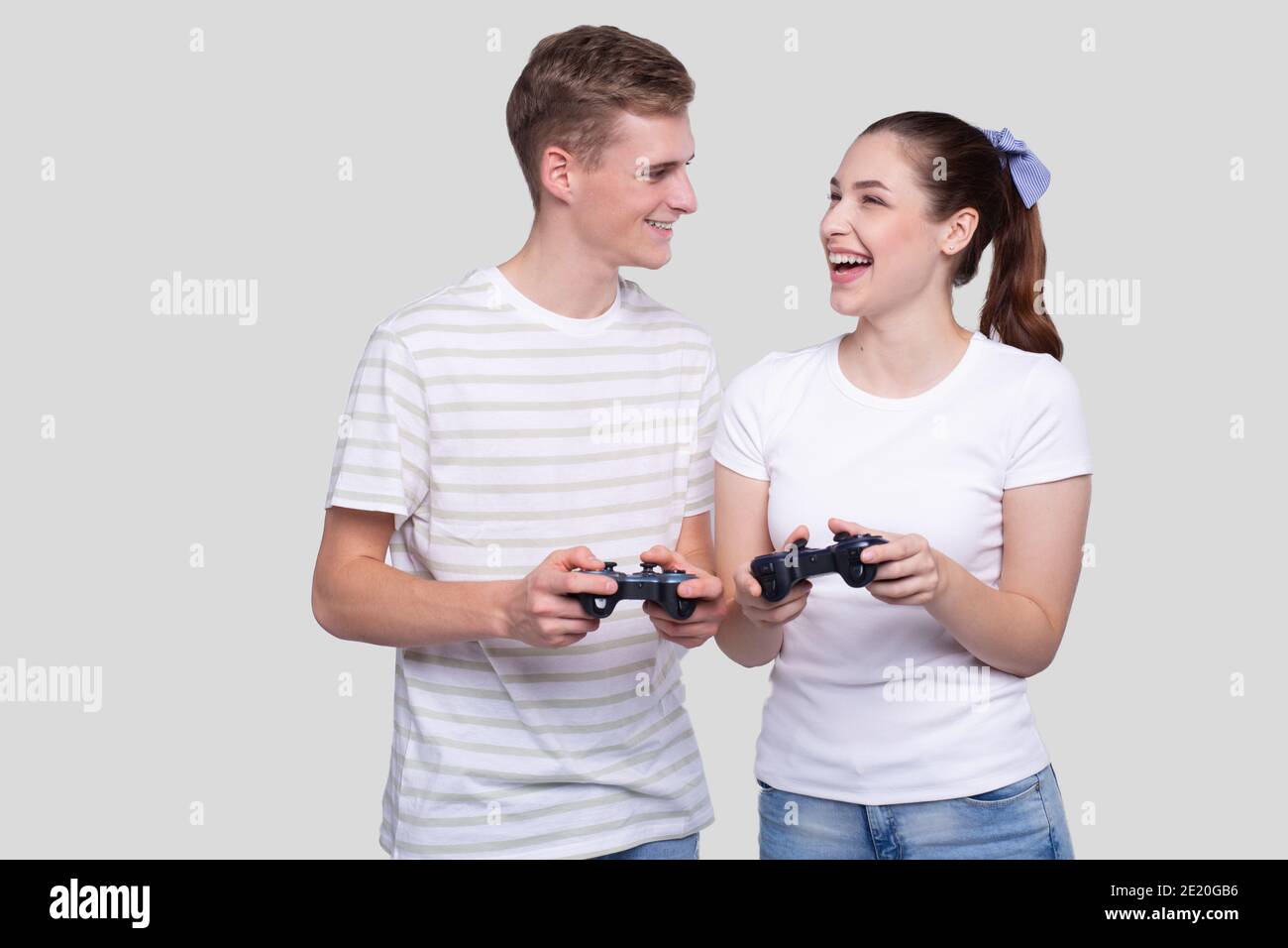 Couple Standing with Joysticks in Hands Looking at Each Other Smilling Isolated Stock Photo