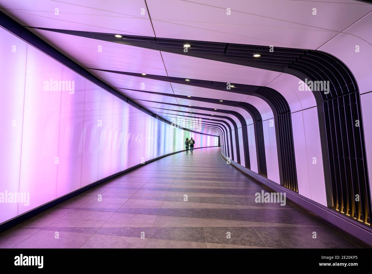 Colourful light tunnel with two people walking in distance Stock Photo