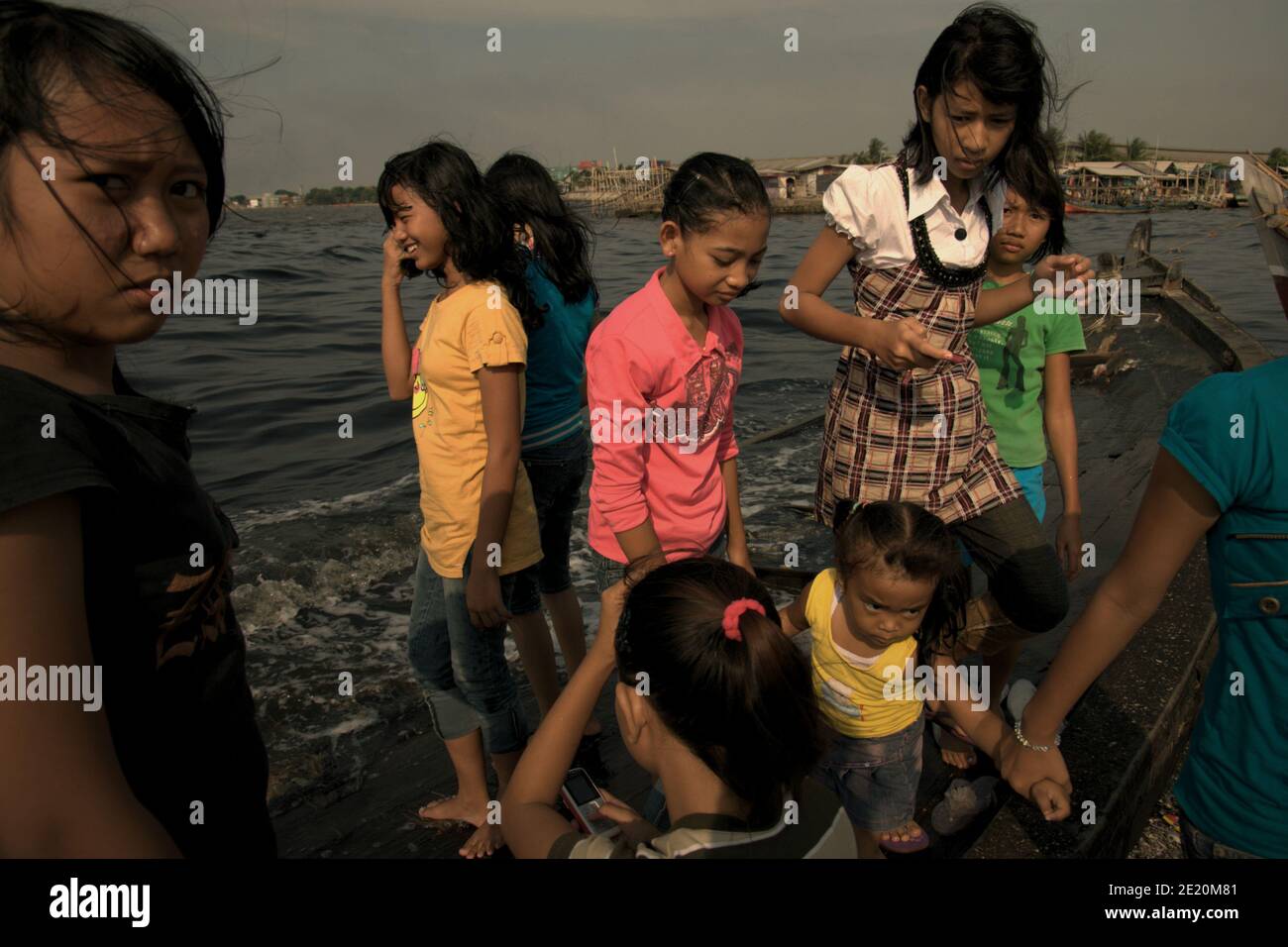 Teenagers having a leisure time on a broken boat tied to the beach in the fishing village of Cilincing, on the coastal area of Jakarta, Indonesia. Archival photo (2008). Stock Photo