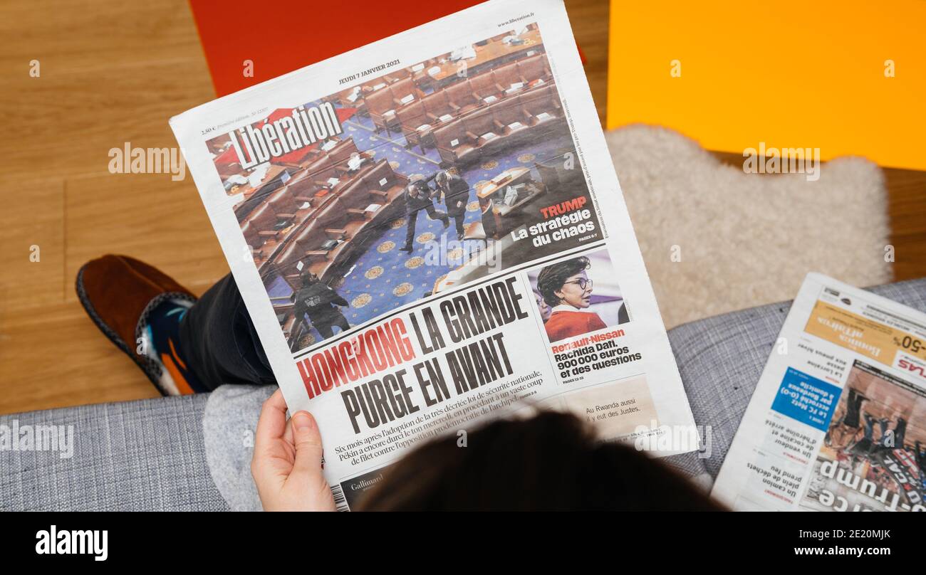 Paris, France - Jan 7, 2020: Woman reading on couch French newspaper Liberation in front page show storming of the U.S. Capitol by supporters of U.S. President Donald Trump on January 07, 2021 Stock Photo