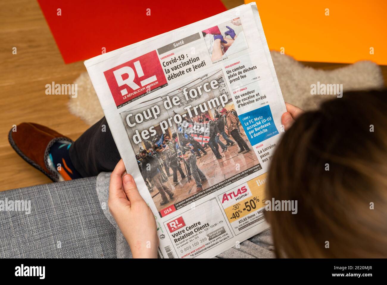 Paris, France - Jan 7, 2020: Woman reading French newspaper Le republicain Lorrain front page show storming of the U.S. Capitol by supporters of U.S. President Donald Trump on January 07, 2021 Stock Photo