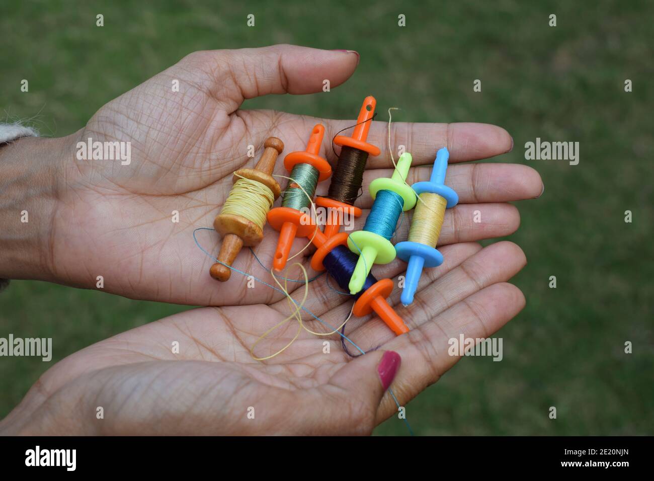 Collection of miniature spools, thread rolls called as Manjha or maanja in hand palms. Toy spools manja on the occasion of kite flying festival uttara Stock Photo