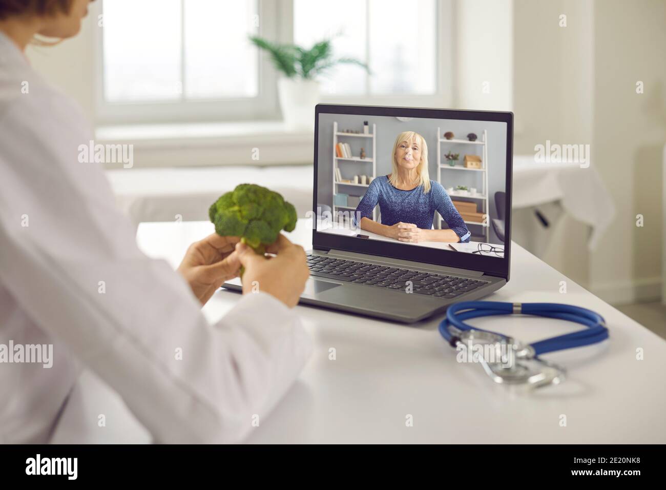 Doctor video calling senior client and telling her about benefits of healthy diet Stock Photo