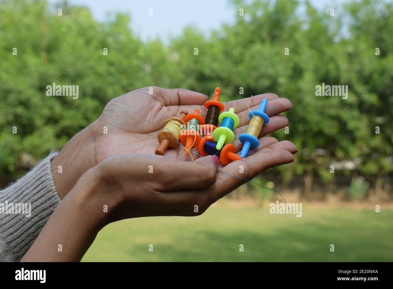 Collection of miniature spools, thread rolls called as Manjha or maanja in hand palms. Toy spools manja on the occasion of kite flying festival uttara Stock Photo