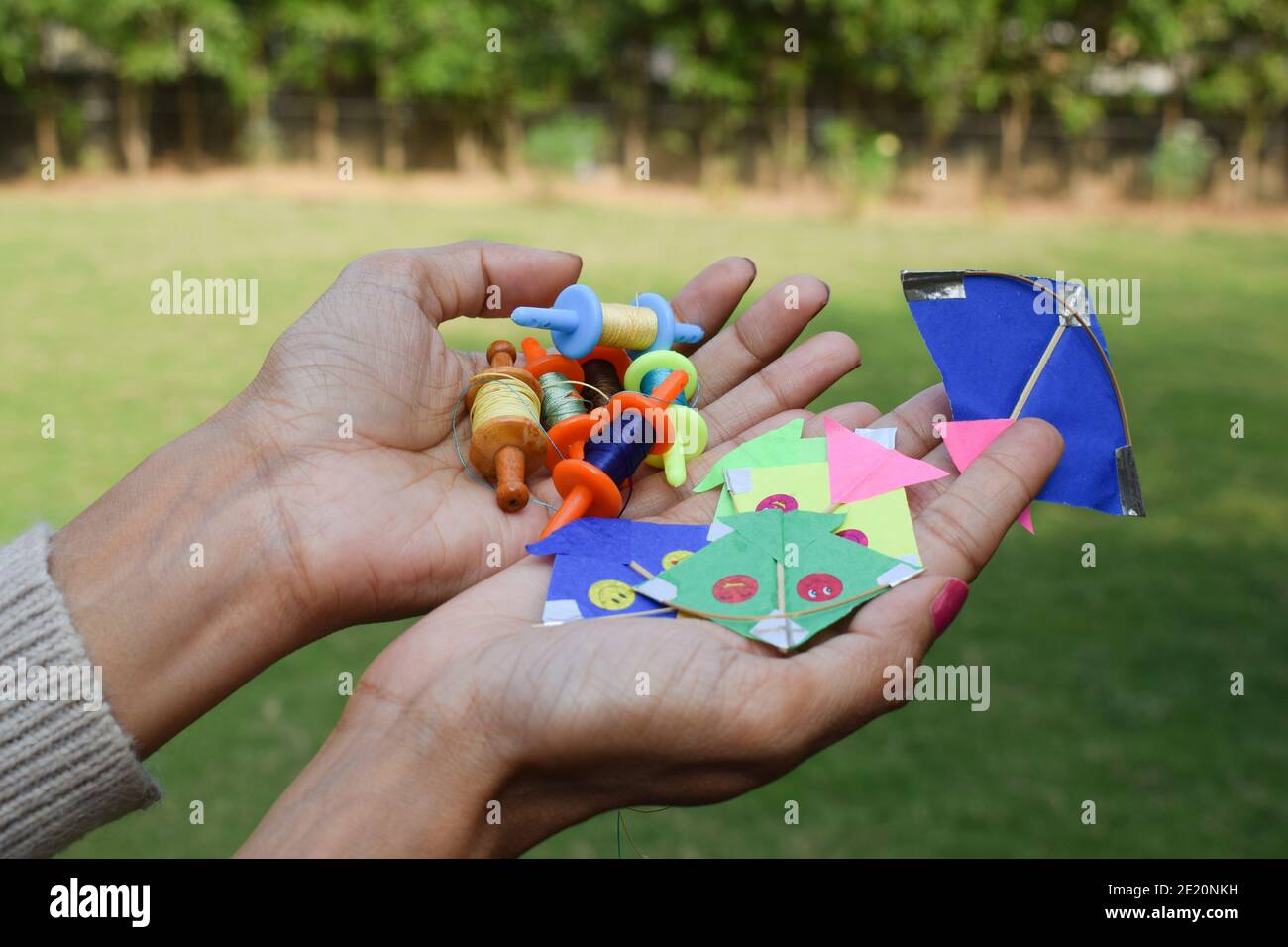 Collection of miniature spools and kites, thread rolls called as Manjha or maanja in hand palms. Toy spools manja on the occasion of kite flying festi Stock Photo