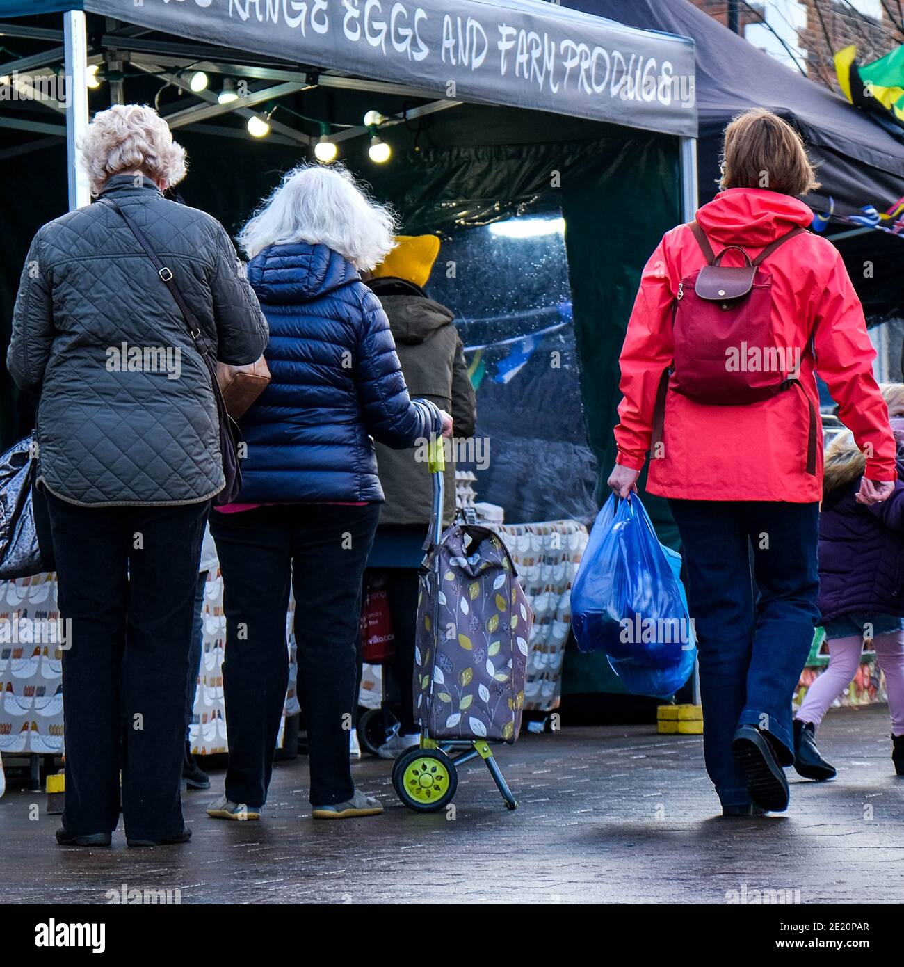 London UK, Small Group Of People Shopping At An Outdoor Market Stall Selling Fresh Farm Produce Stock Photo
