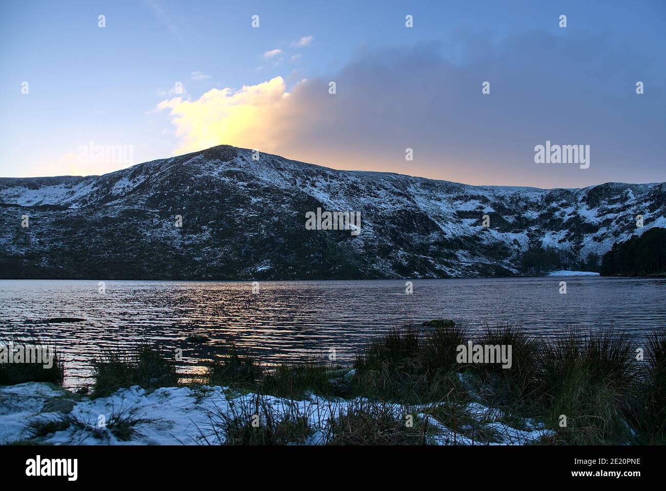 Stunning sunset above snowy Eagles Crag peak and Lough Bray Lower lake